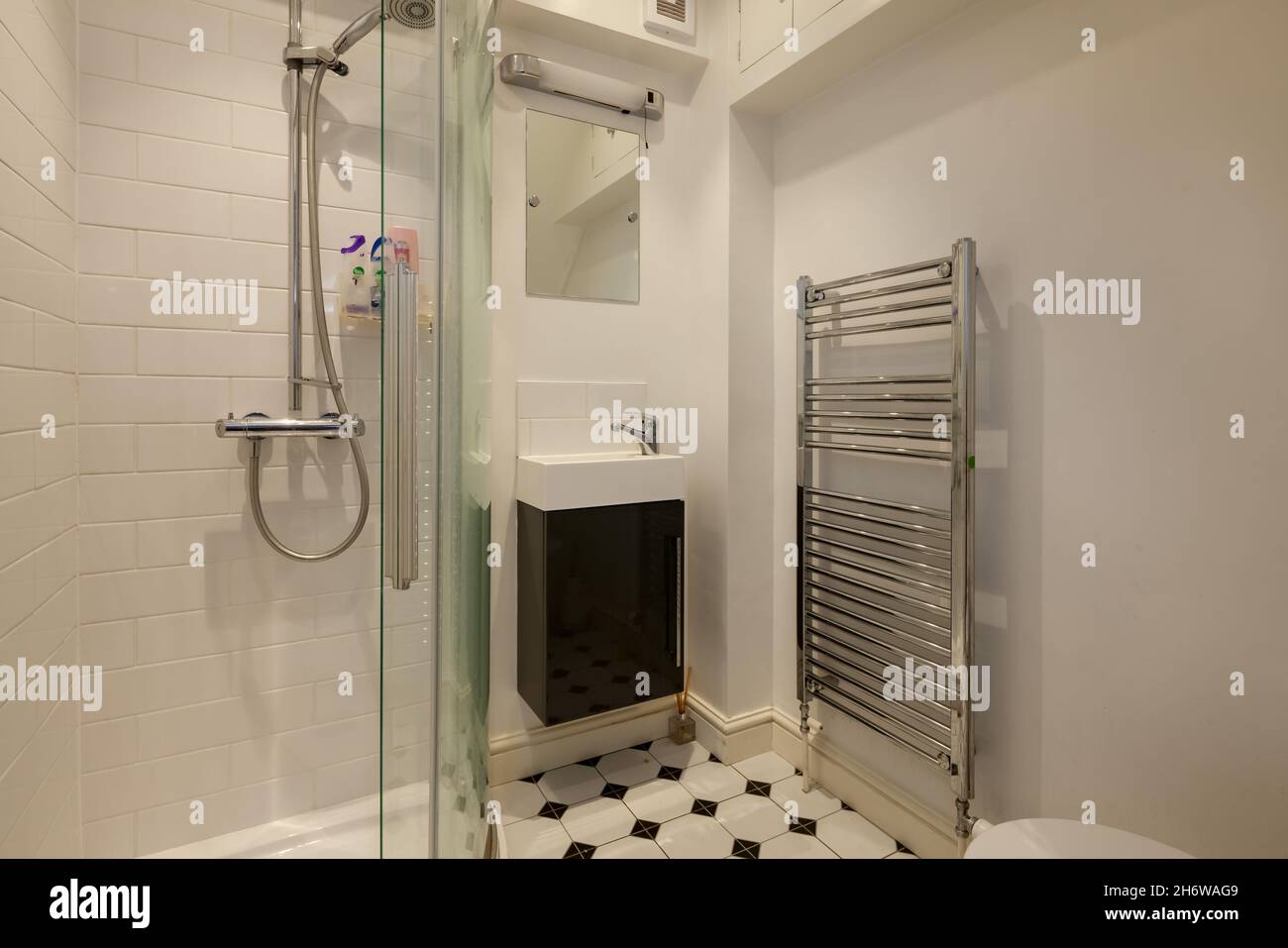 Cambridge, Angleterre - août 15 2019 : salle de douche avec panneau de verre et armoire carrelée, porte-serviettes et lavabo Banque D'Images