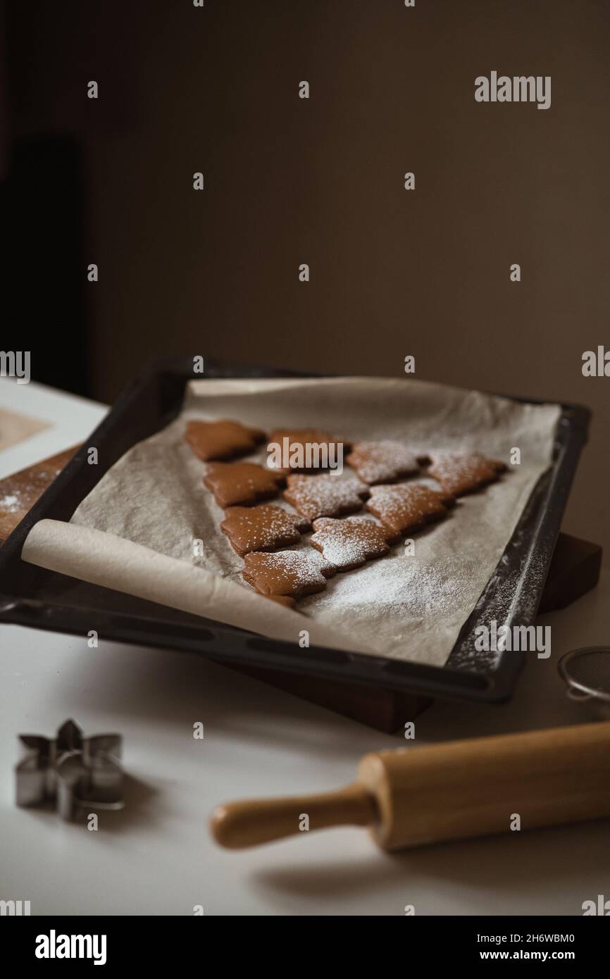 La forme de l'arbre de Noël est faite de pain d'épice et en poudre avec du sucre.Prêt de produits cuits sur une plaque de cuisson dans la cuisine, vacances d'hiver sp Banque D'Images