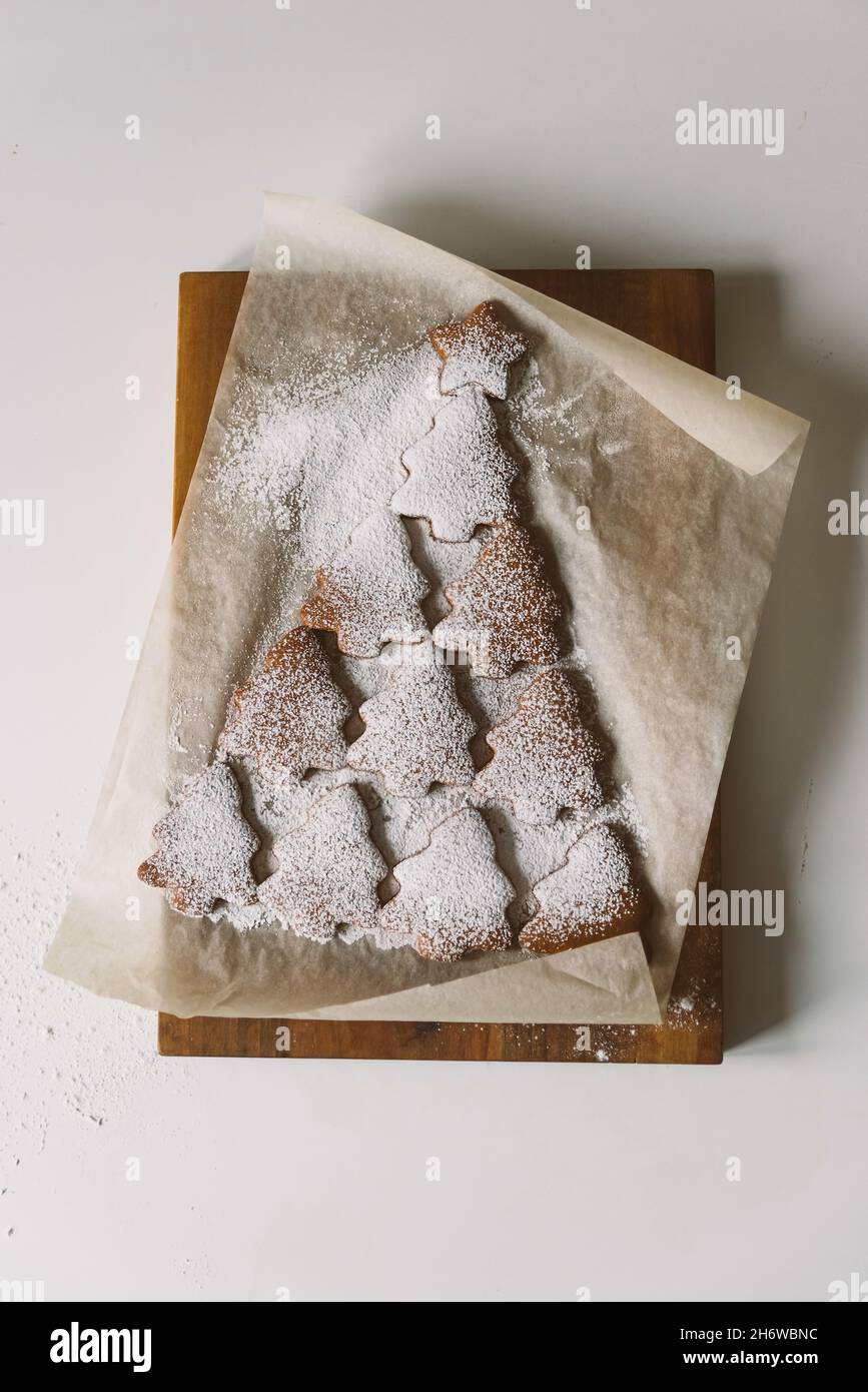 Arbre de Noël en pain d'épice parsemé de sucre en poudre sur parchemin.Concept créatif de Noël et du nouvel an, minimalisme, gros plan, pose à plat Banque D'Images