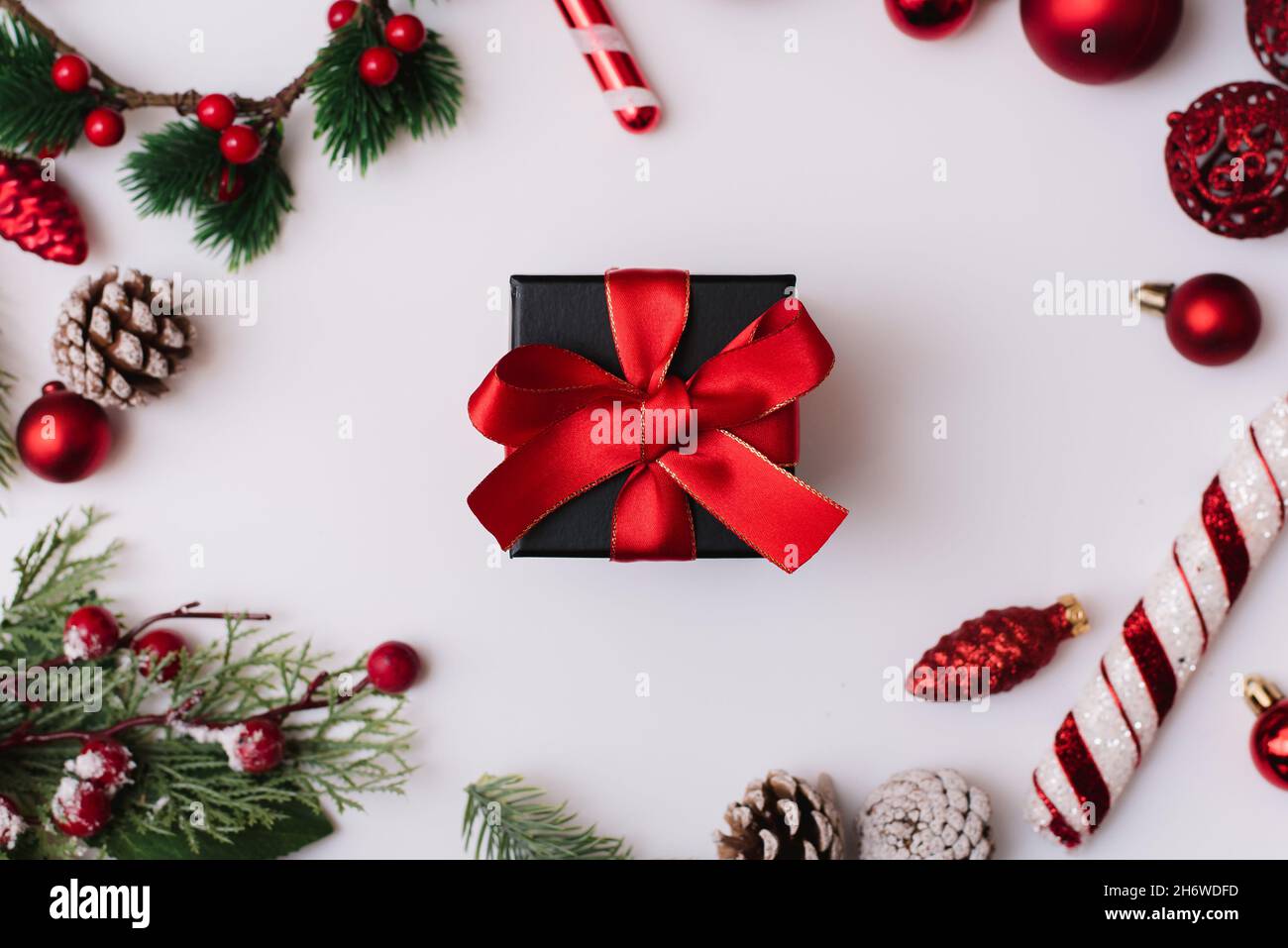 Cadeau de Noël avec noeud rouge sur fond blanc avec branches de sapin et décorations sur fond blanc.Vue de dessus Banque D'Images