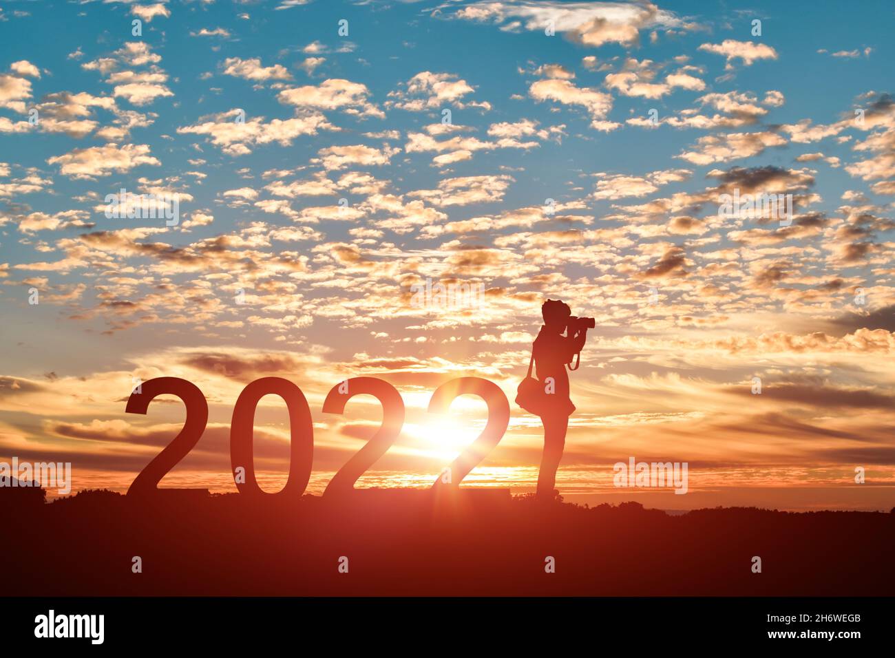 Silhouette de photographe prenant des photos en 2022 ans au lever ou au coucher du soleil.Idée pour une bonne année 2022. Banque D'Images