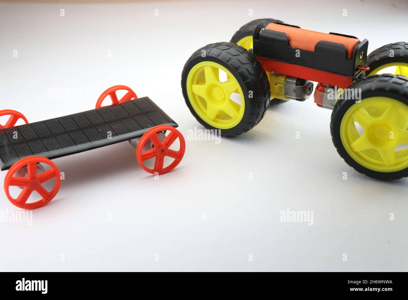 Mini voiture électrique et petite voiture solaire modèles de travail côte à côte comparaison isolée sur blanc, projets scientifiques utiles Banque D'Images