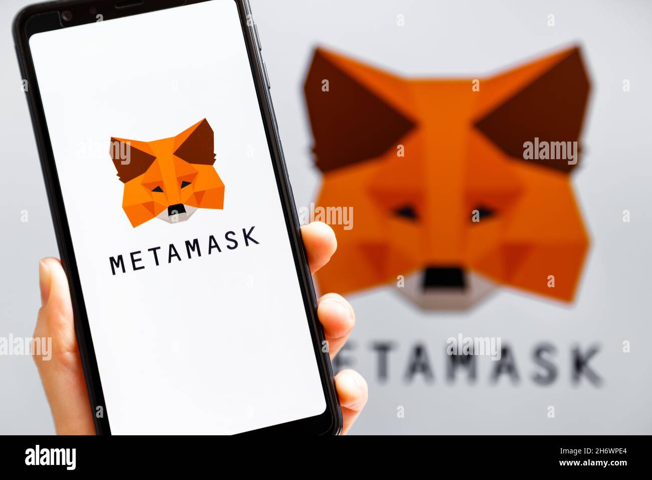 Ukraine, Odessa - octobre, 9 2021: Main tenant mobile avec l'application MetaMask fonctionnant à l'écran de smartphone avec le logo MetaMask en arrière-plan.MetaMask l'est Banque D'Images