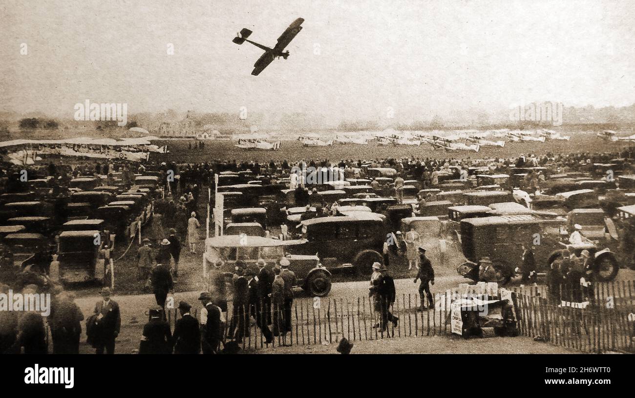 Un spectacle aérien de la RAF (air show) à Hendon en 1927 montrant un avion léger survolant le parking rempli de véhicules d'époque Banque D'Images