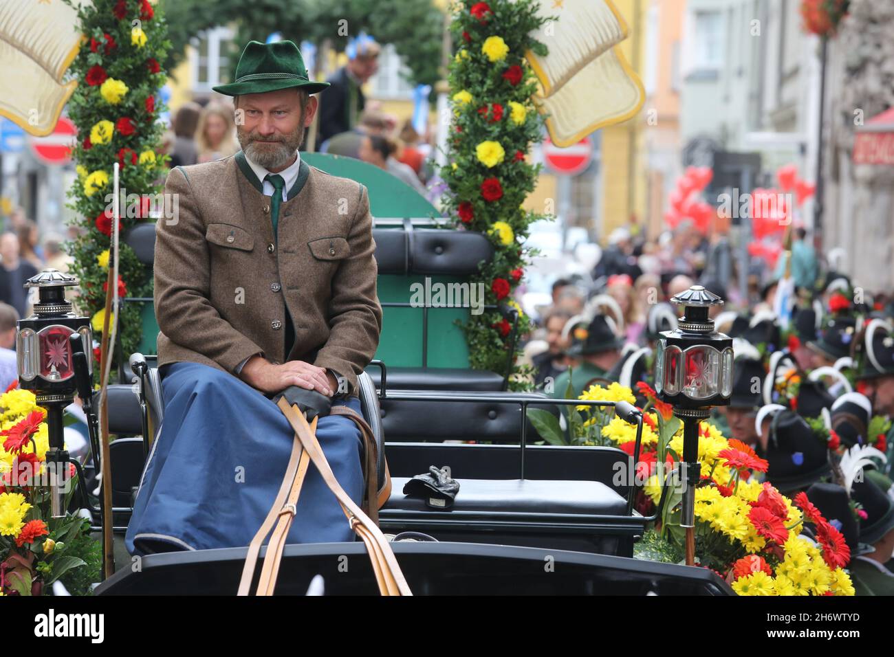 Une voiturette habitée par un homme dans une veste et un chapeau bavarois traditionnels au début de la parade de l'Oktoberfest. Banque D'Images