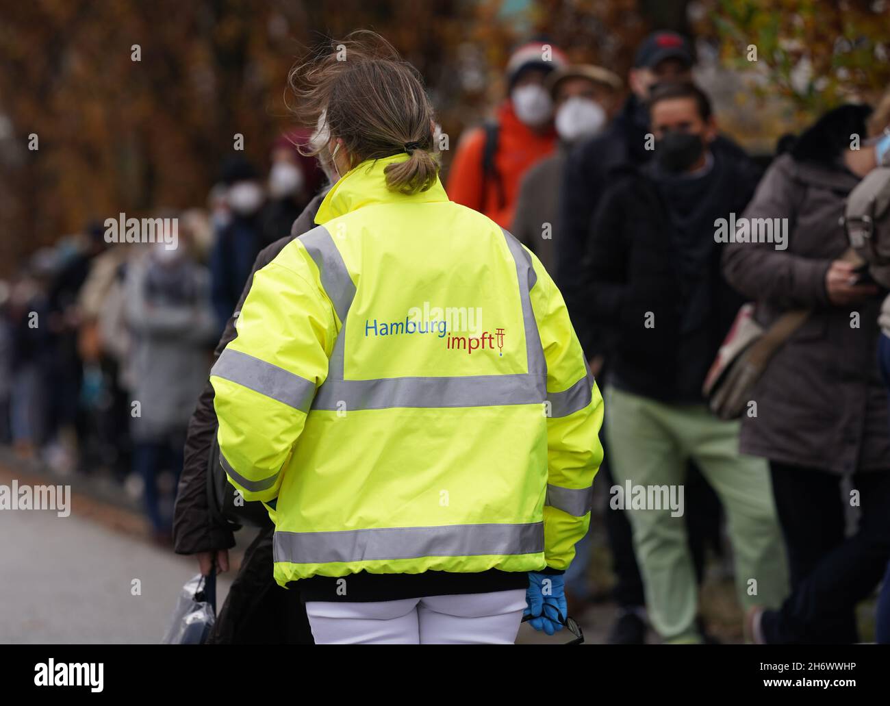 Hambourg, Allemagne.18 novembre 2021.Un membre du personnel de l'équipe mobile de vaccination se trouve à côté des personnes en attente devant la Bibliothèque centrale de Hambourg lors d'une campagne de vaccination à la Bibliothèque centrale de la Bücherhallen dans le centre-ville, plusieurs centaines de personnes faisaient la queue vers midi.La file d'attente s'étendait sur la piste à environ 200 mètres dans une petite rue.(À dpa 'longue file d'attente à l'action de vaccination dans les salles de livres de Hambourg') Credit: Marcus Brandt/dpa/Alamy Live News Banque D'Images