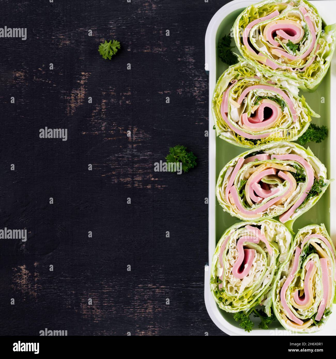 Panier repas sain avec tortillas enveloppés de jambon, fromage et laitue.Vue de dessus, plan d'appartement Banque D'Images