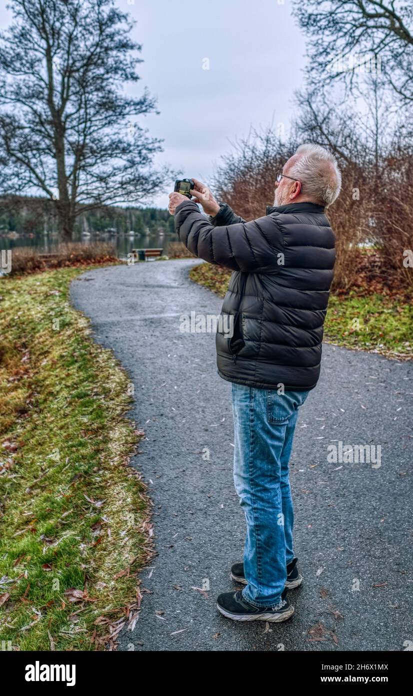 Homme âgé prenant des photos avec son téléphone portable de paysage d'automne Banque D'Images