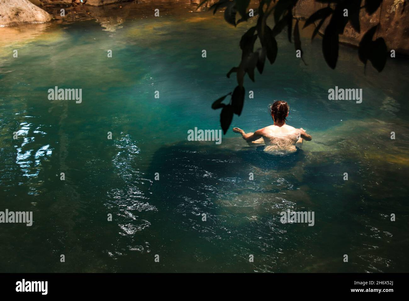 Vue panoramique d'un homme qui se détend dans une piscine cachée dans une forêt Banque D'Images