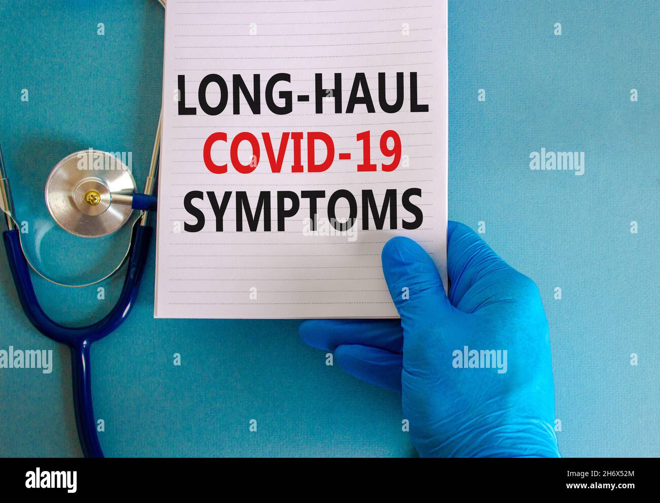 COVID-19 symbole symptômes de covid long-courrier.Carte blanche avec mots long-haul covid-19 symptômes.Main du médecin, stéthoscope, fond bleu, espace de copie.Moi Banque D'Images