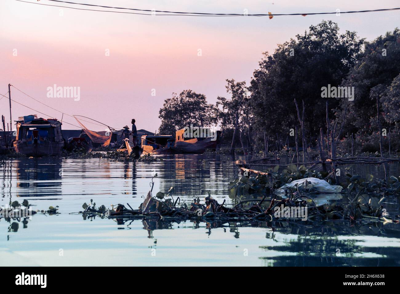 Silhouette d'un pêcheur qui jette un filet de pêche dans le delta du Mékong montrant la vie et la culture du peuple vietnamien Banque D'Images