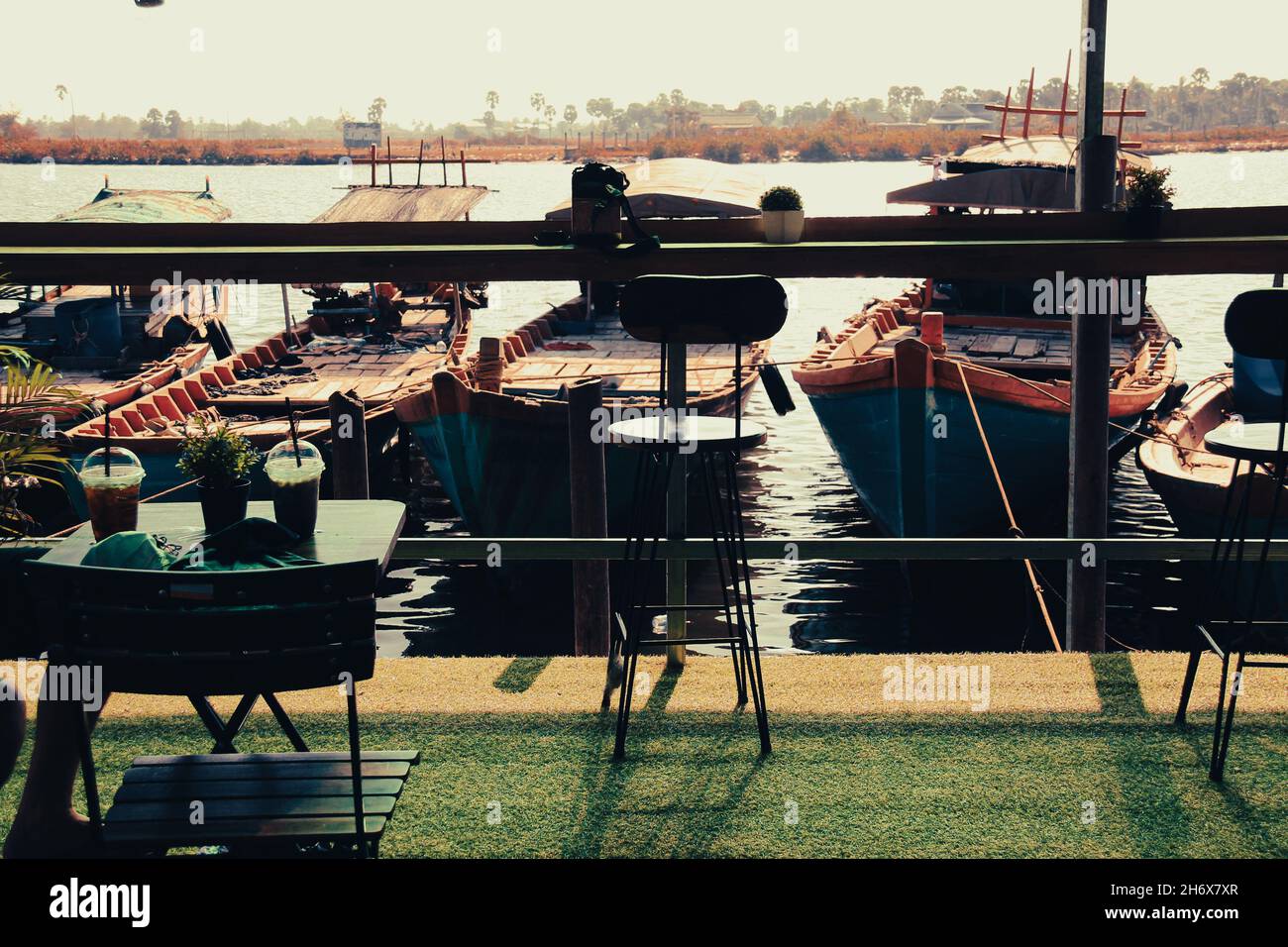 Une tasse de café glacé sur la table avec la vue des bateaux de pêche Khmers en amarrage en arrière-plan Banque D'Images