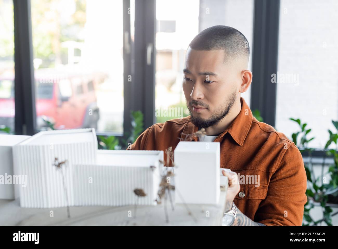 architecte asiatique barbu regardant un projet de construction flou avec des modèles de maison Banque D'Images