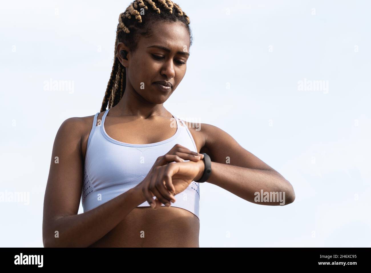 Bonne fille africaine utilisant la montre intelligente pour la routine d'entraînement de sport - Focus sur le visage Banque D'Images