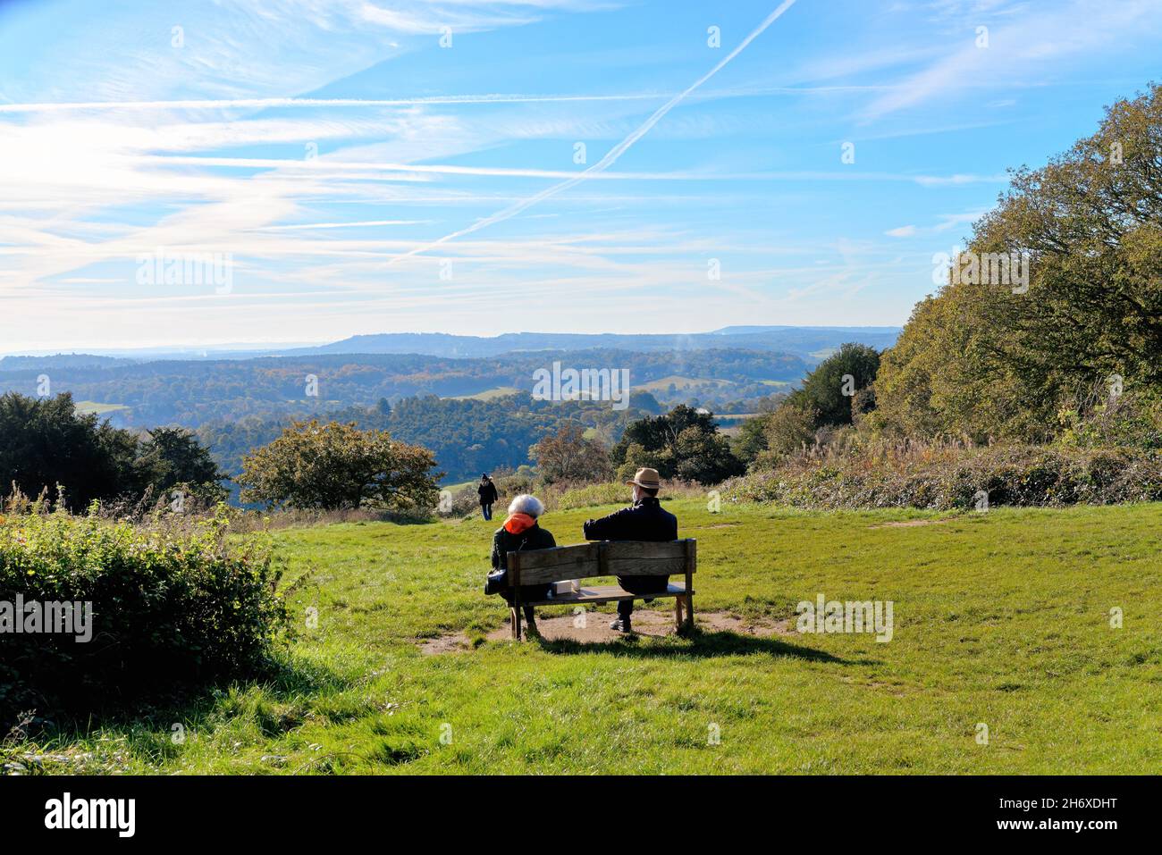 Un couple âgé qui profite de la journée d'automne ensoleillée assis sur un banc au-dessus des North Downs à Newlands Corner près de Guildford Surrey, Angleterre, Royaume-Uni Banque D'Images