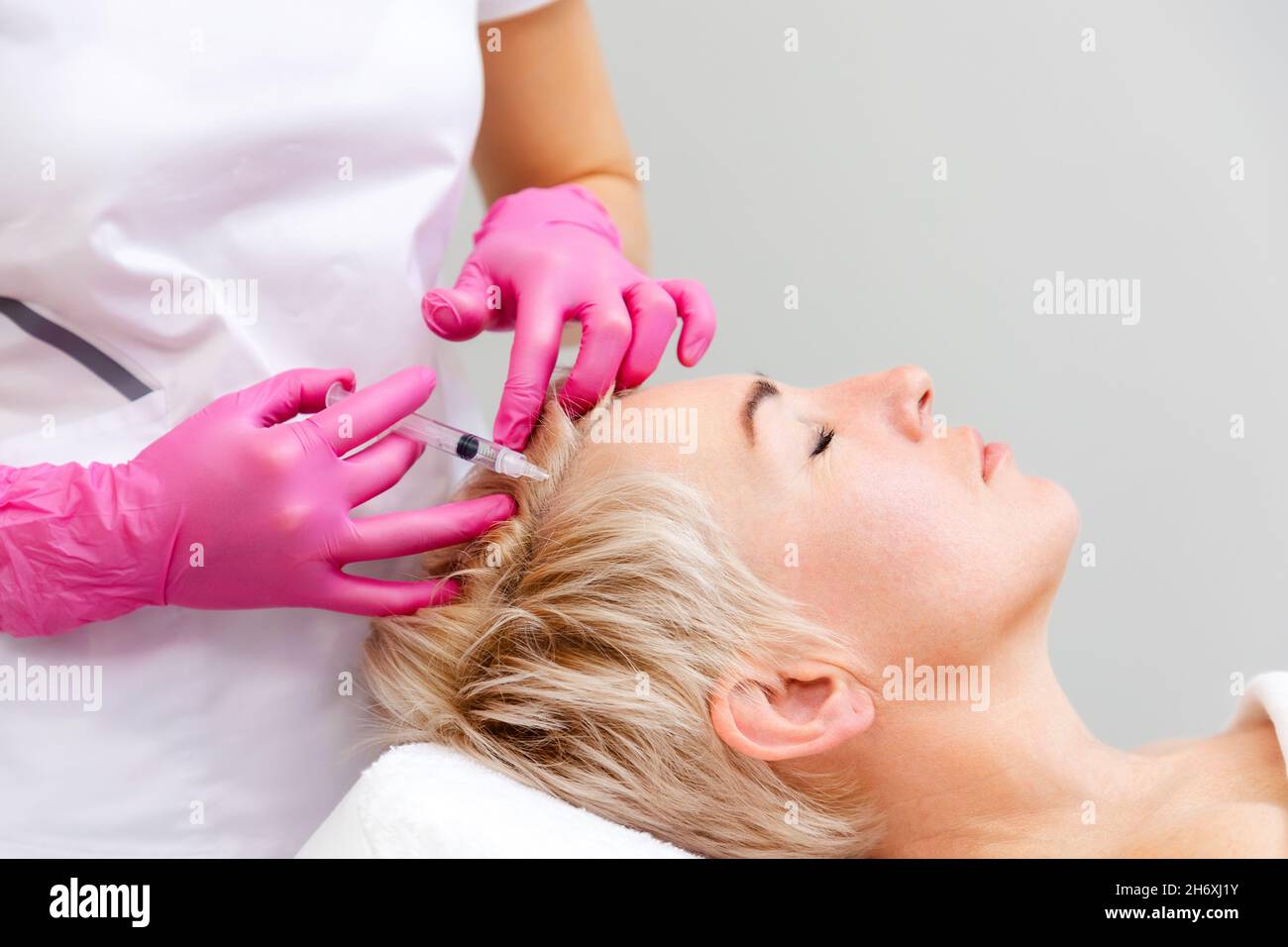 Esthéticienne professionnelle médecin en gants médicaux roses tenant la  seringue de remplissage faisant l'injection sur le front.Traitement  anti-âge et mésothérapie en cos Photo Stock - Alamy