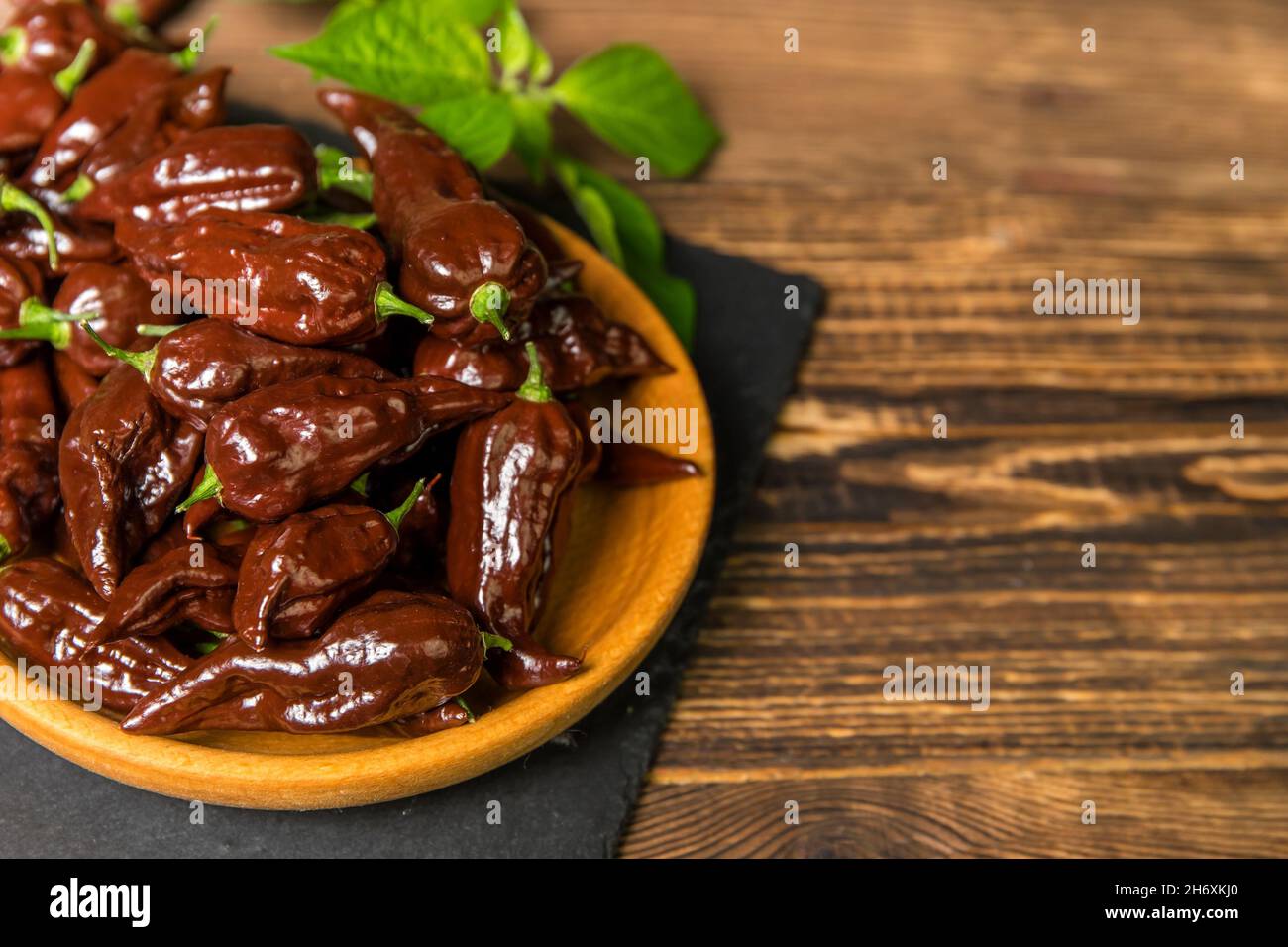 Piment sur fond de bois.piment très chaud.Chocolat Naga Bhut Jolokia.Épices exotiques.Ingrédients chauds pour la nourriture. Banque D'Images