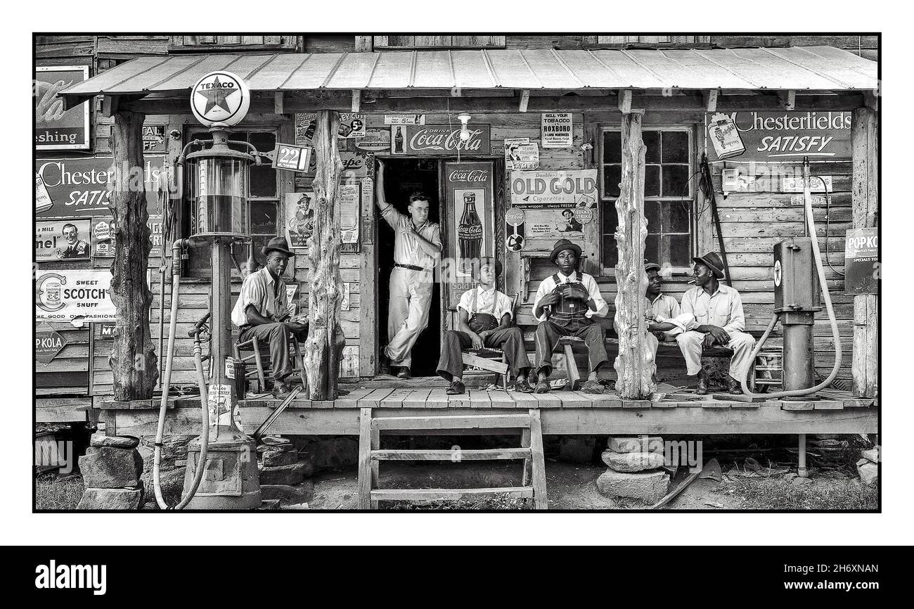 1940s États-Unis American Gas station de remplissage de carburant en Amérique du Sud dans le 1940s avec des travailleurs prenant une pause sur la façade typique rustique de station de service en bois avec variété de produits publicitaires américains plaques et affiches de l'époque Banque D'Images