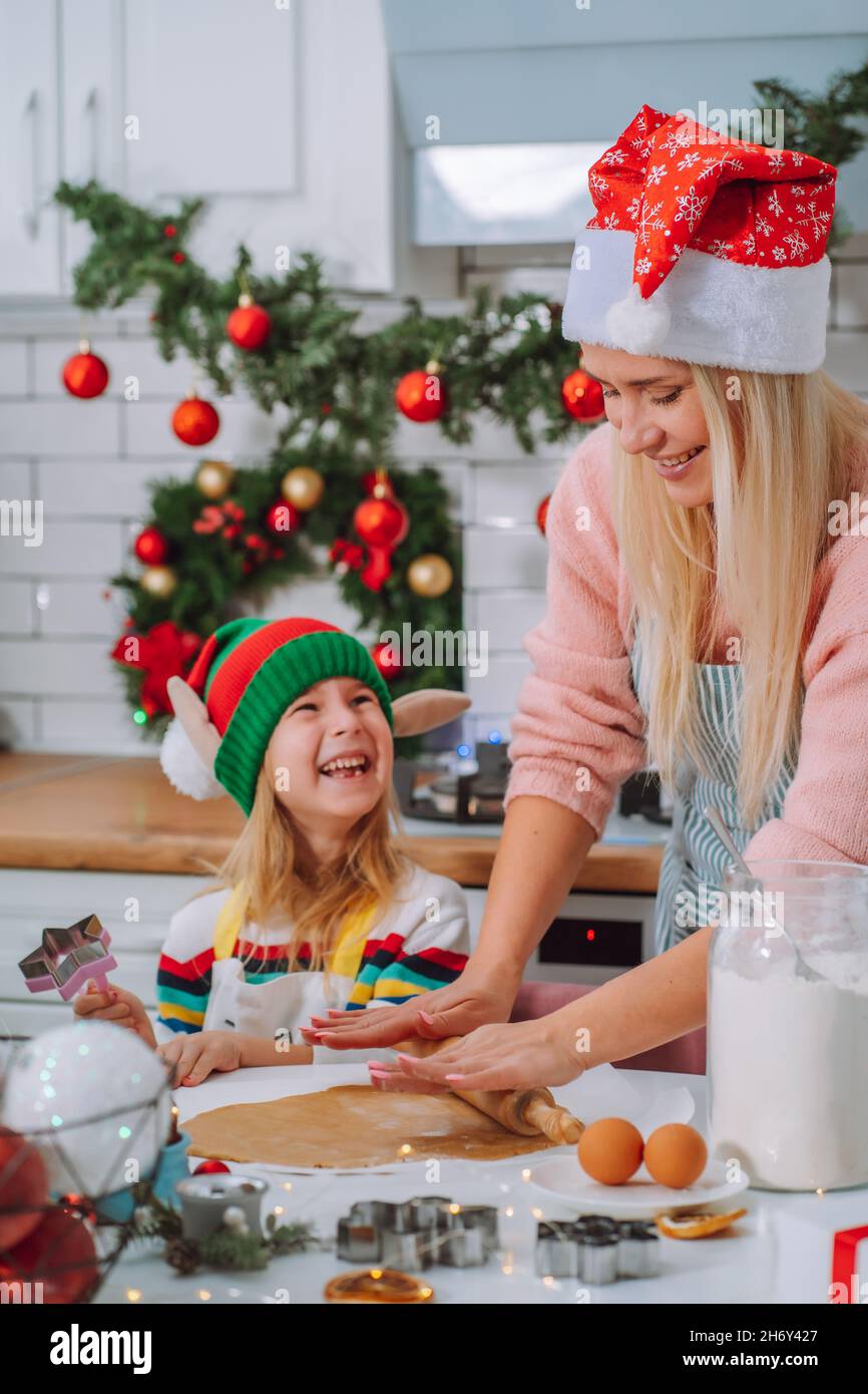 La famille de la mère et de la fille font du pain d'épice maison pour noël dans la cuisine décorée à la maison.Ambiance de Noël, préparation. Banque D'Images