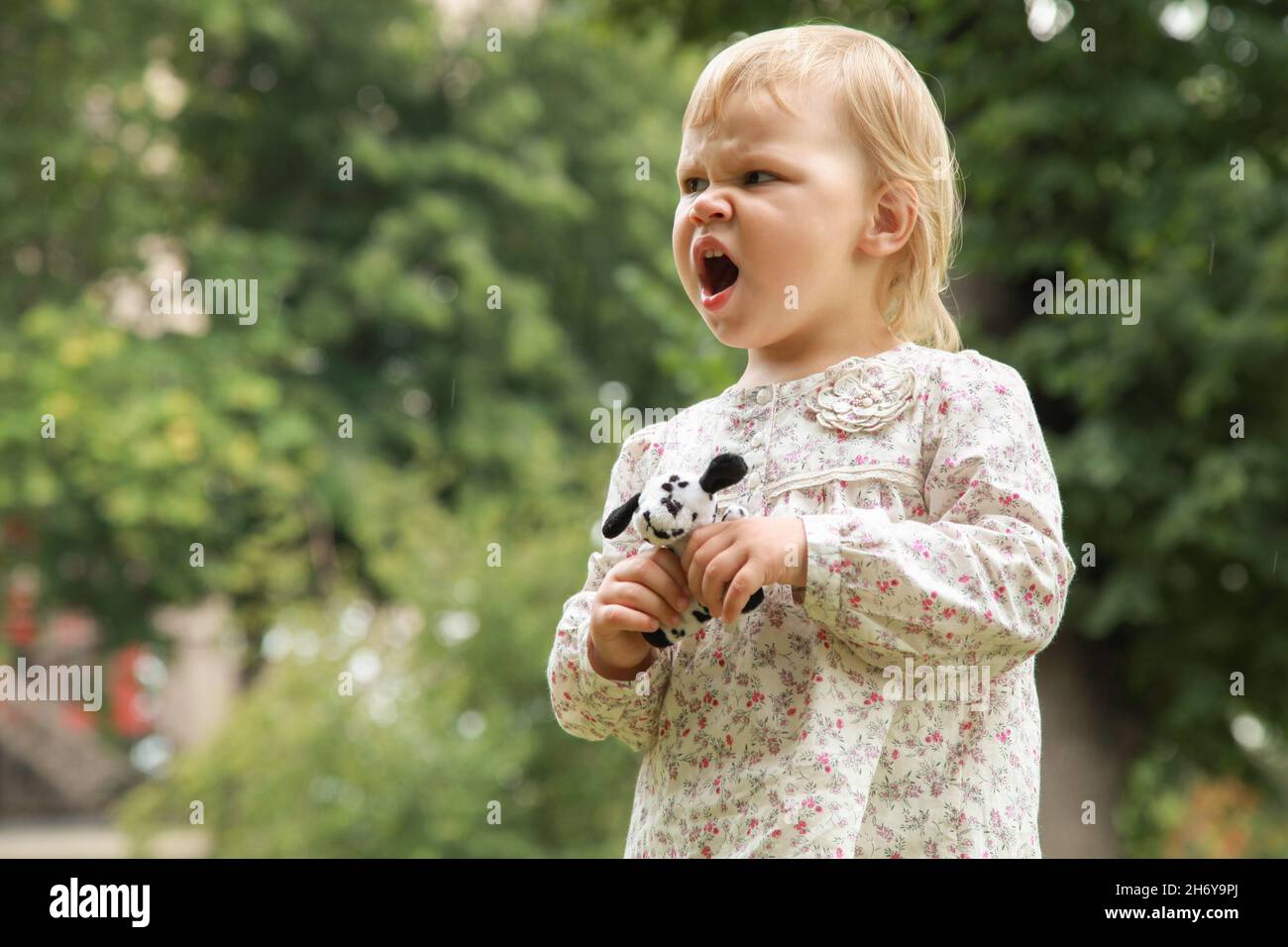 Une jeune fille blonde en colère avec un jouet dans les mains crie Banque D'Images