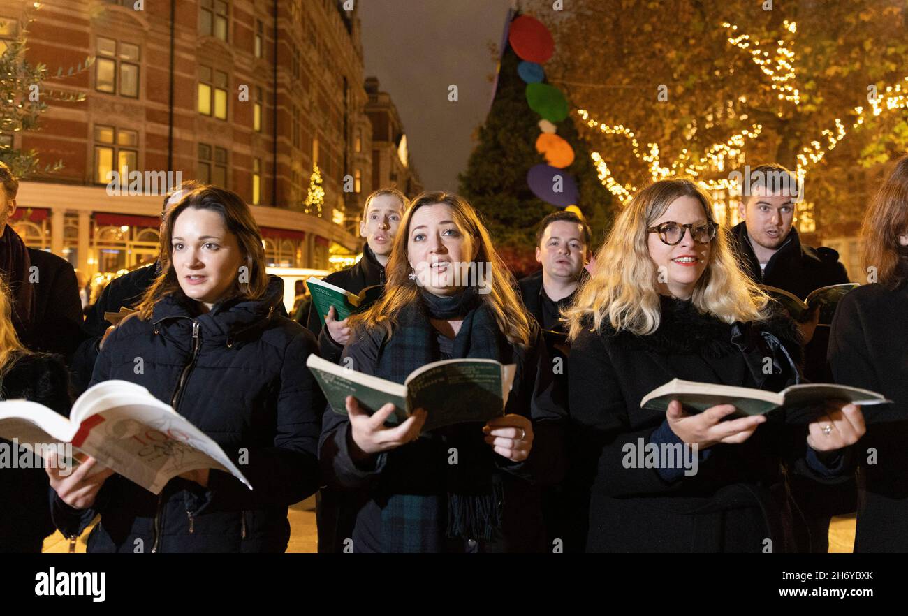 USAGE ÉDITORIAL SEUL Un chœur se produit devant l'arbre de Noël devant l'hôtel Connaught de Mayfair, Londres, lorsque les lumières sont allumées.Date de la photo: Jeudi 18 novembre 2021. Banque D'Images