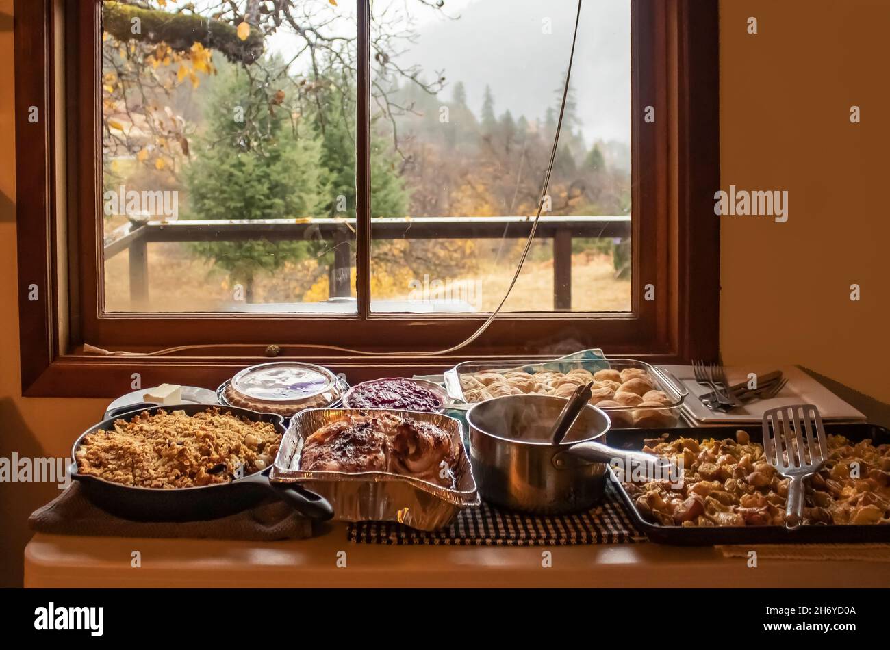 Le dîner de Thanksgiving est servi dans des casseroles sur la table près de la fenêtre donnant à l'extérieur de la cabine dans les bois le jour de la pluie Banque D'Images