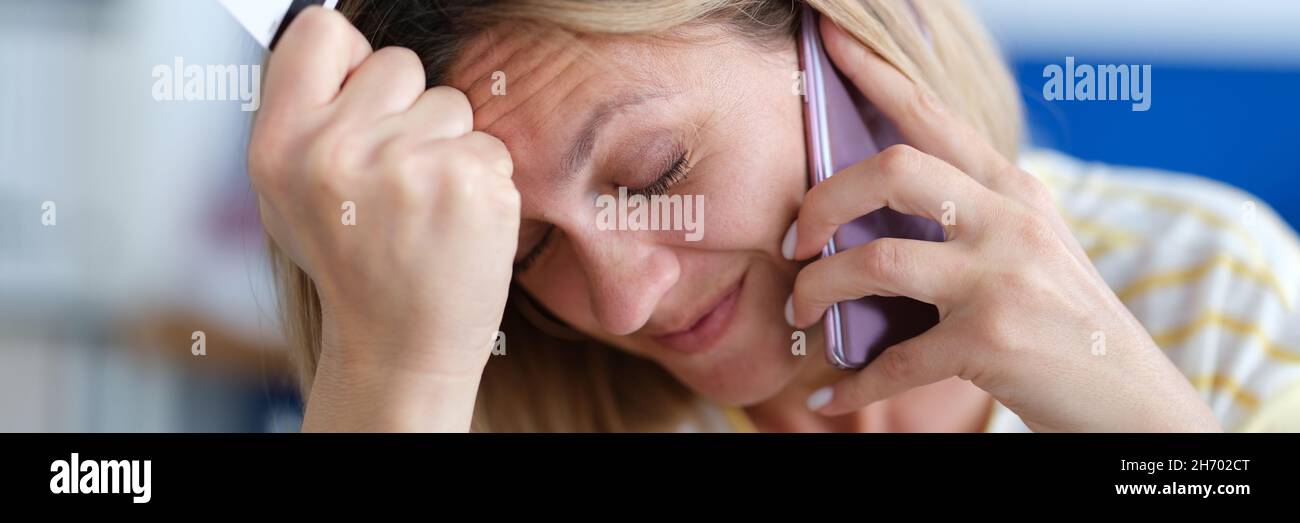 Une femme contrariée parlant au téléphone et tenant une carte bancaire en plastique Banque D'Images