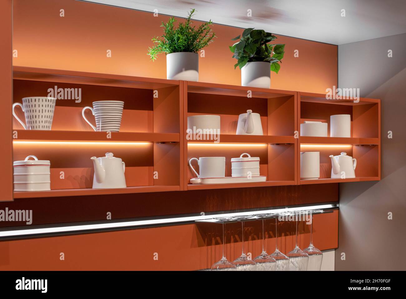 Exposition décorative de céramique blanche sur une étagère de cuisine en bois montée sur un mur avec un rack de verres propres dans un décor intérieur a Banque D'Images