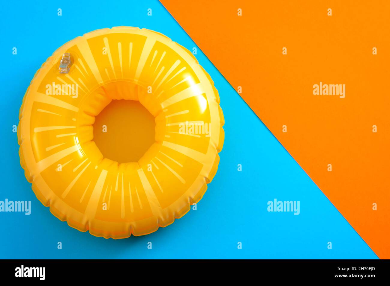 Vacances d'été et équipement de sécurité pour la natation avec une bouée de vie isolée sur un fond minimaliste orange et bleu avec espace copie Banque D'Images