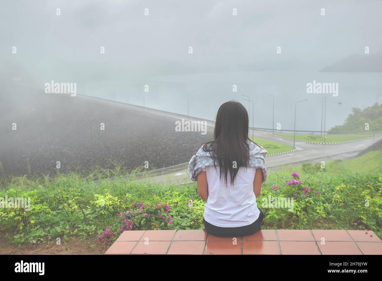 Une seule femme assise seule sur la vue de dessus du barrage avec brouillard le matin Banque D'Images