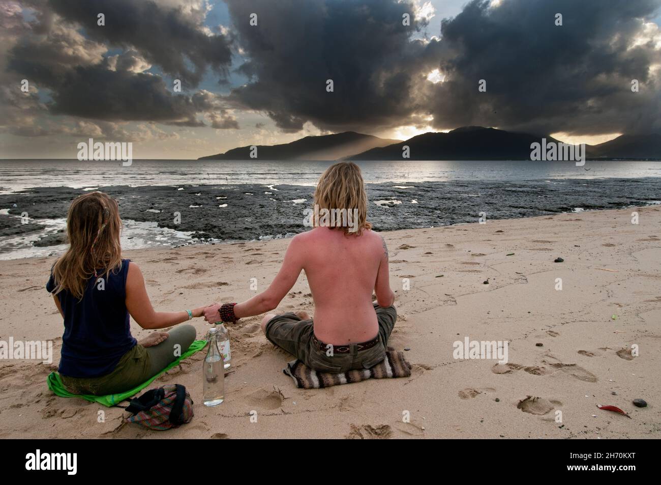 Un jeune couple s'assoit, main dans la main, sur l'esplanade de Cairns dans le Queensland, en Australie, pendant qu'ils regardent les derniers moments de l'éclipse totale du soleil. Banque D'Images