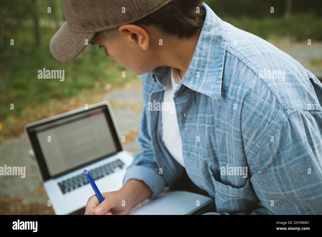 Jeune femme avec bloc-notes et ordinateur portable assis sur un banc Banque D'Images
