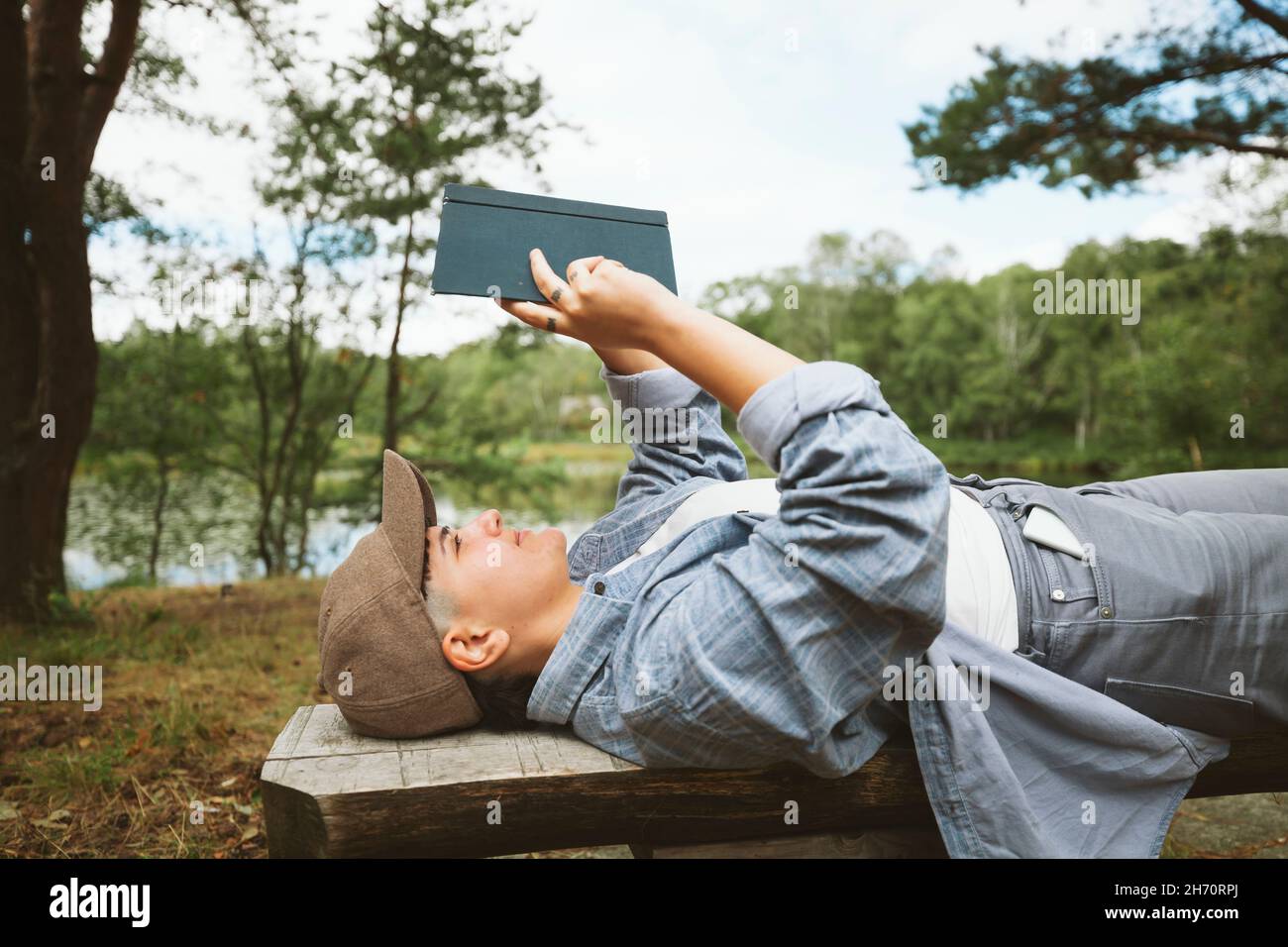 Jeune femme lisant le livre tout en étant allongé sur un banc en bois Banque D'Images