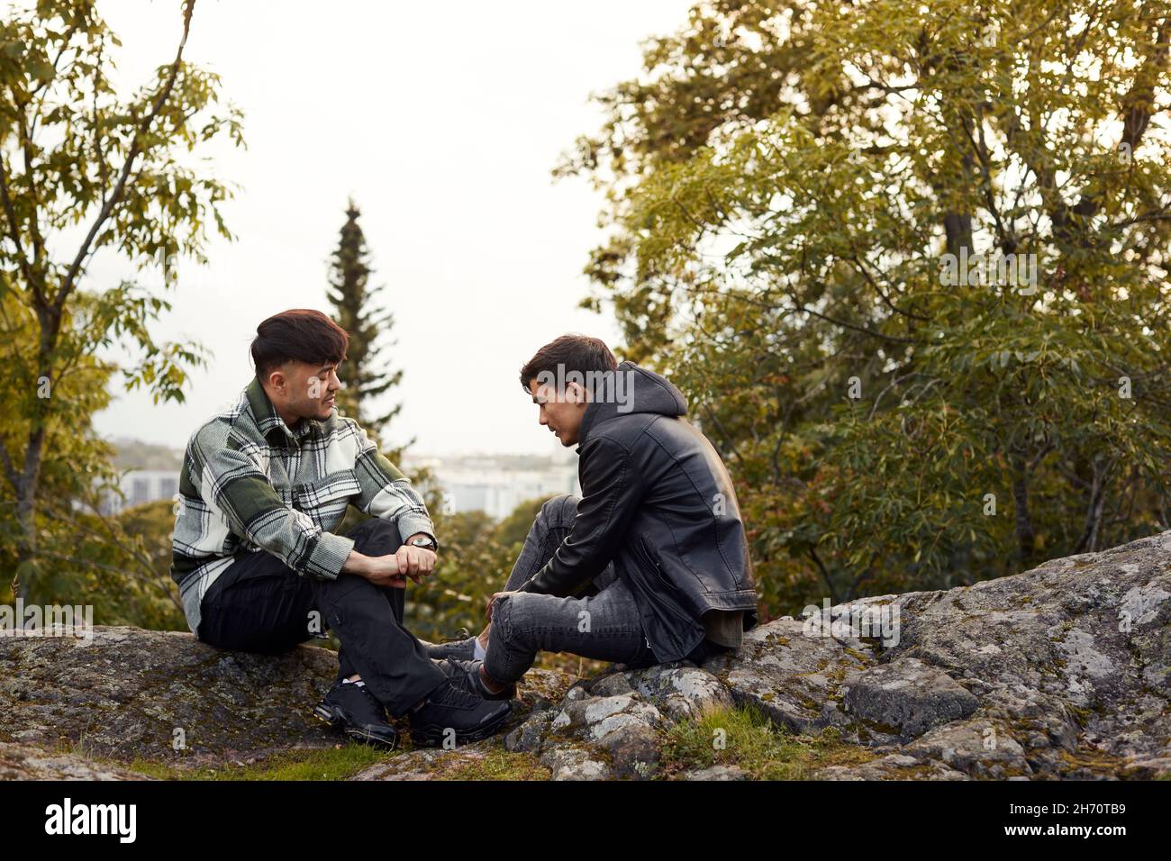 Jeunes hommes assis sur des rochers et parlant Banque D'Images
