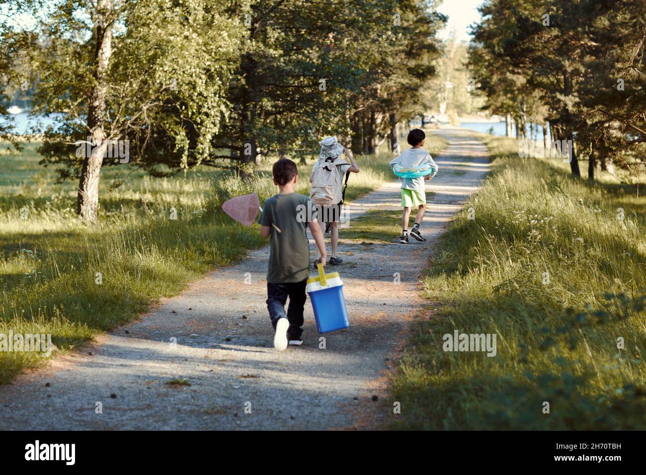 Vue arrière des enfants qui marchent le long de la route de terre Banque D'Images