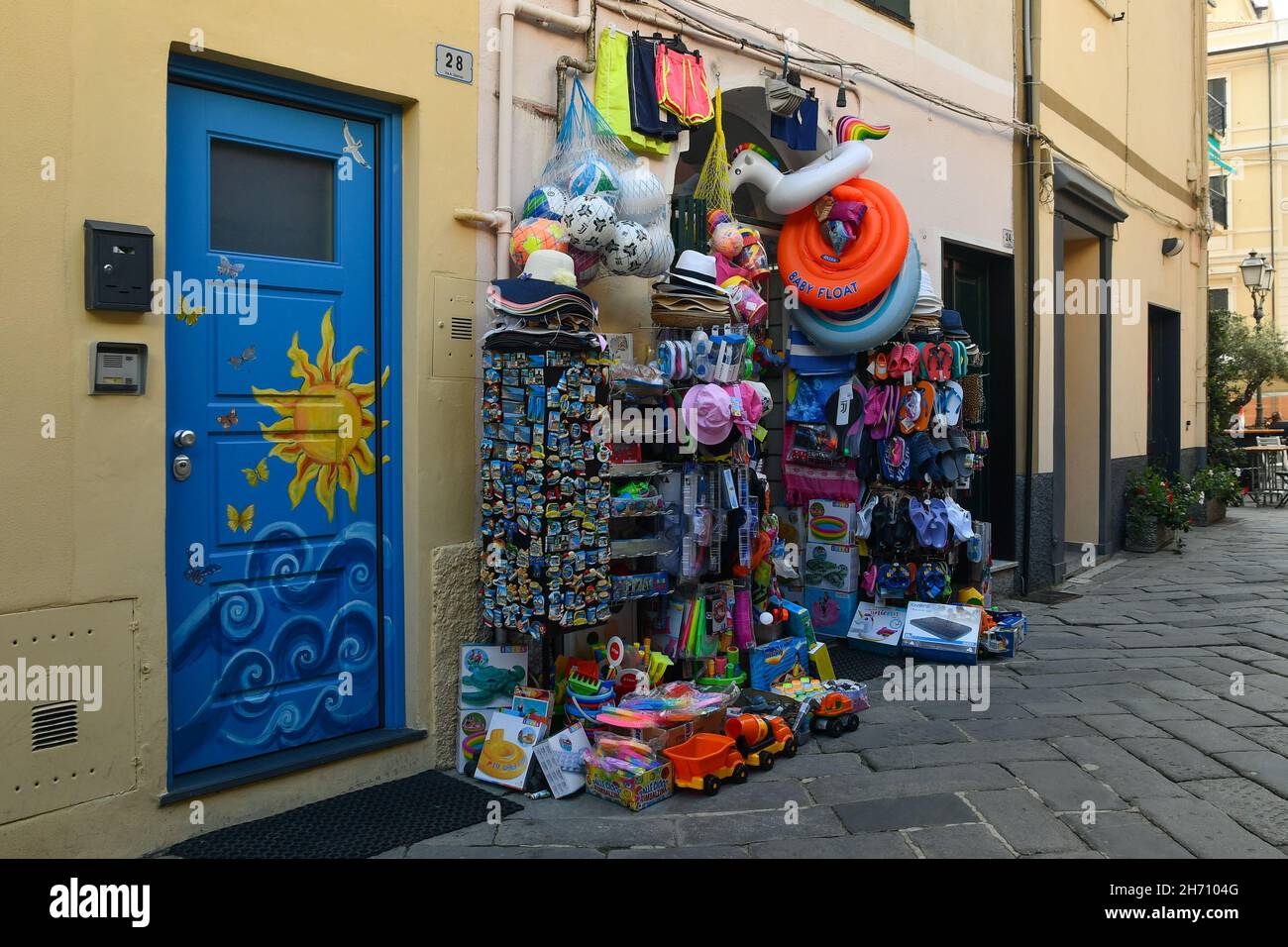 Aperçu d'une allée dans la vieille ville avec une boutique touristique vendant des produits à vol d'eau et des jouets de plage en été, Alassio, Savona, Ligurie, Italie Banque D'Images