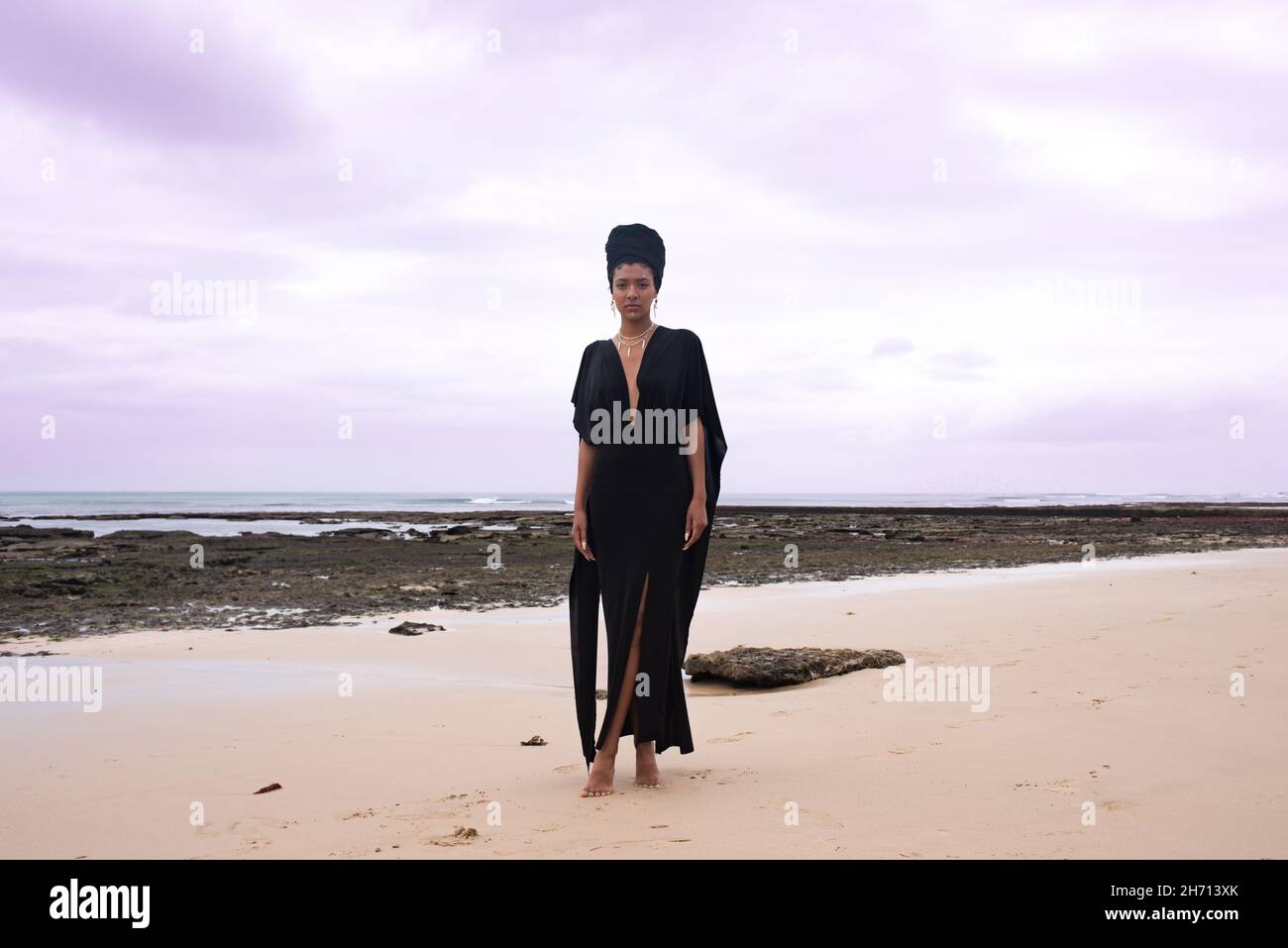 Femme debout le long de la mer avec des rochers en arrière-plan Banque D'Images