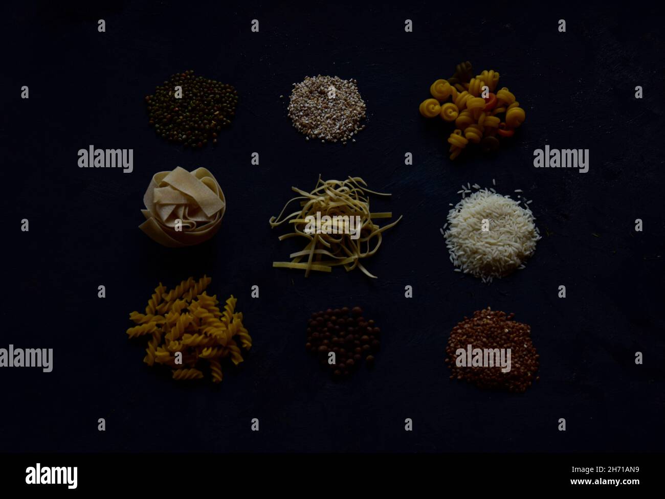 Un ensemble de produits céréaliers crus populaires dans la cuisine, pâtes, porridge, riz sur fond noir Banque D'Images
