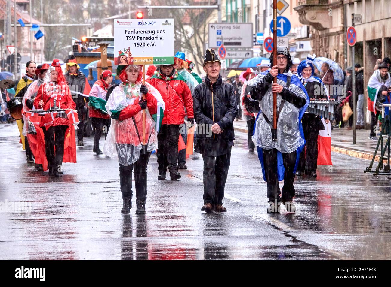 Braunschweig, Allemagne, 23 février 2020 : procession fanfare au défilé de carnaval dans la déverse avec des marches en imperméable transparentes à travers la ville Banque D'Images