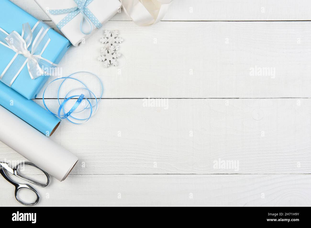 Décoration de Noël - cadeaux de Noël enveloppés de bleu et de blanc sur le côté gauche du cadre avec espace de copie. Banque D'Images