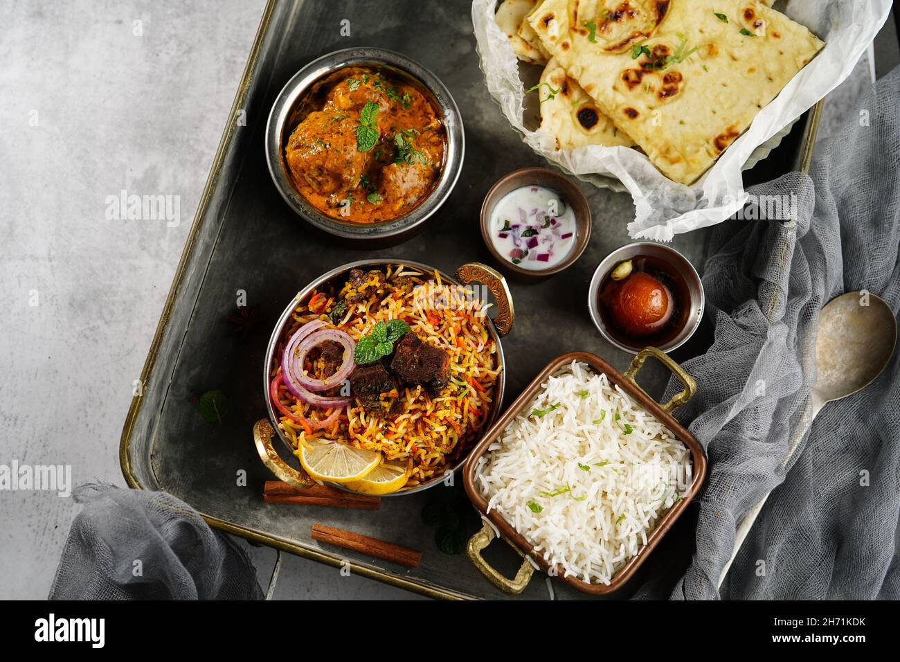 Repas indien thali - Mutton biryani, raita, kafta malai, riz basmati, naan de beurre et jamun gulab servi sur un plateau Banque D'Images