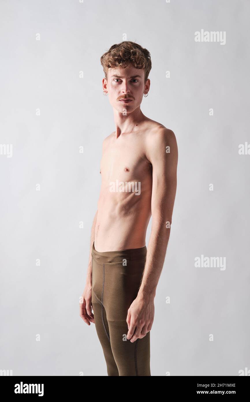 un jeune garçon blond a été exposé à la moustache et porte des boucles d'oreilles debout regardant l'appareil photo Banque D'Images