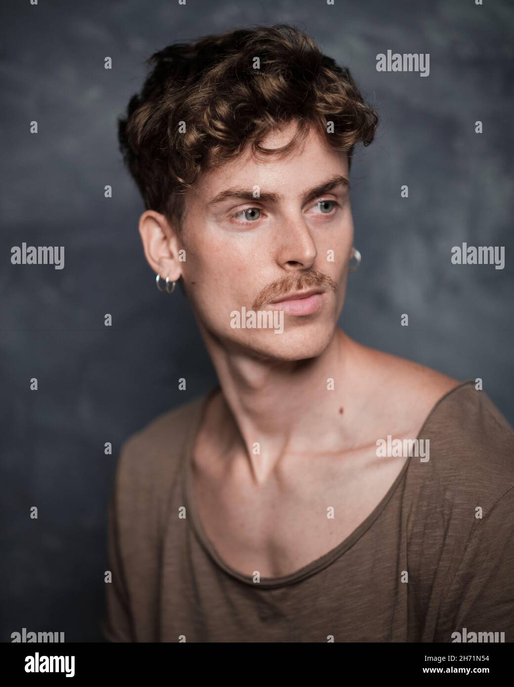 Portrait sélectif d'un jeune homme blond avec des yeux bleus et une moustache sur un fond peint à la main Banque D'Images