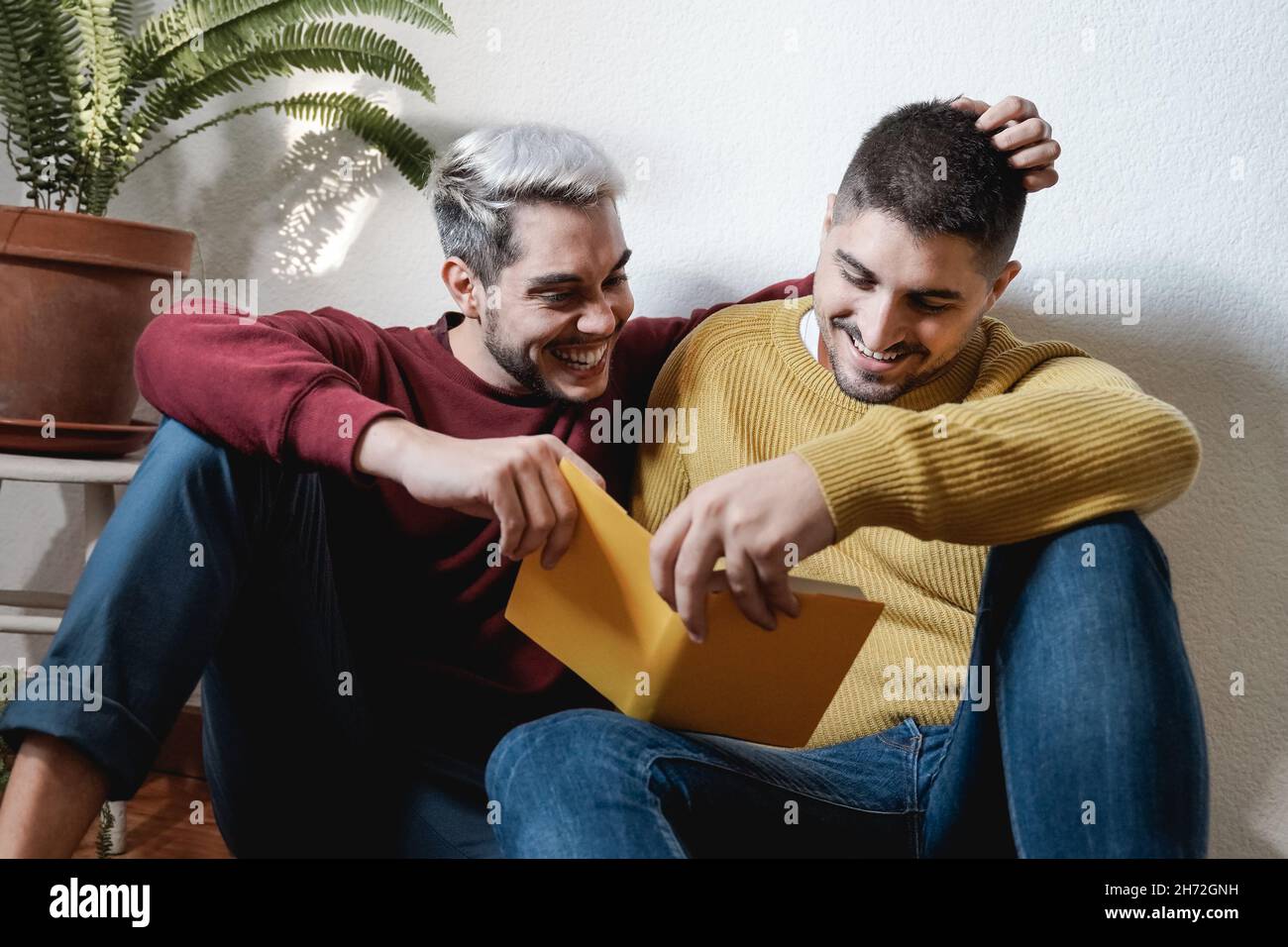 LGBT gay couple embrassant et lire livre ensemble intérieur à la maison - Homosexual amour et romance concept Banque D'Images