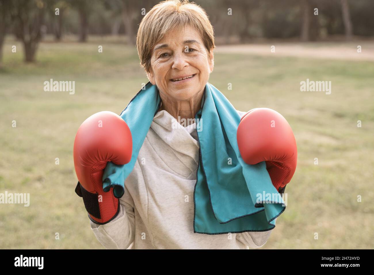 Femme âgée souriant à la caméra après avoir suivi un entraînement de boxe en plein air au parc de la ville - Focus on face Banque D'Images