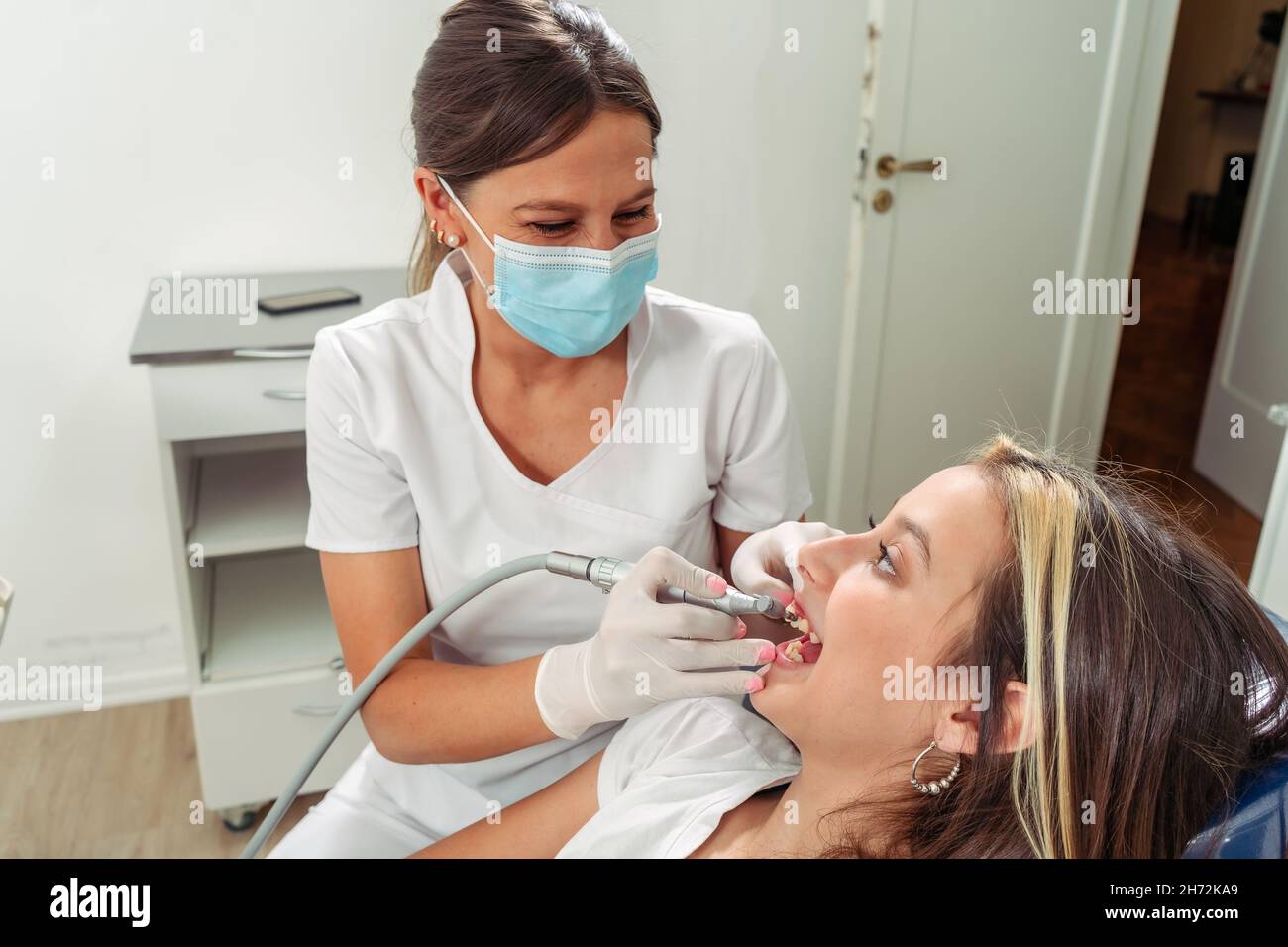 Jeune dentiste féminin effectuant un traitement de tour sur un patient adolescent.Concept soins dentaires, soins de santé. Banque D'Images
