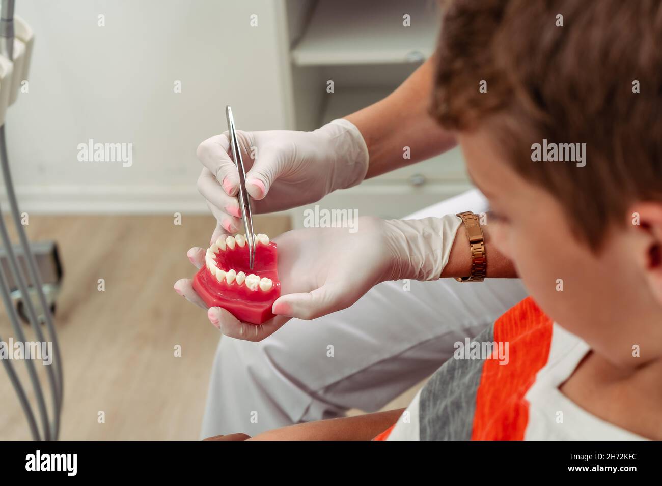 À l'aide d'un modèle dentaire, le dentiste féminin montre à l'enfant quel traitement il doit traiter.Concept soins dentaires, soins de santé. Banque D'Images