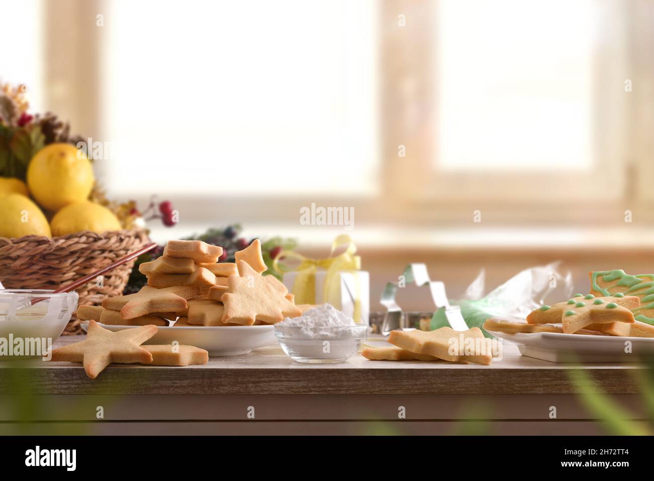 Table en bois avec biscuits aux formes de Noël fraîchement cuites sur l'assiette avec décoration de Noël dans la cuisine.Vue avant.Composition horizontale. Banque D'Images
