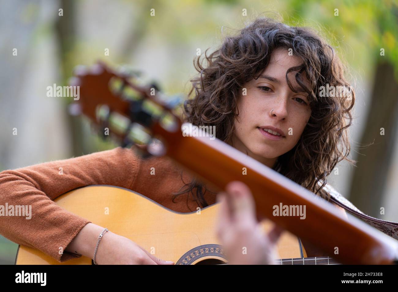 Jeune femme apprenant à jouer de la guitare acoustique dans le parc avec un professeur Banque D'Images