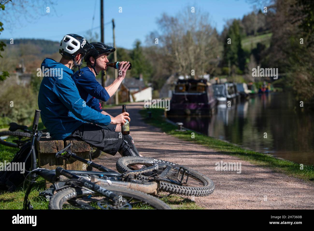 Deux motards de montagne terminent leur balade avec une bière à côté du canal Monbucshire & Brecon, au pays de Galles. Banque D'Images